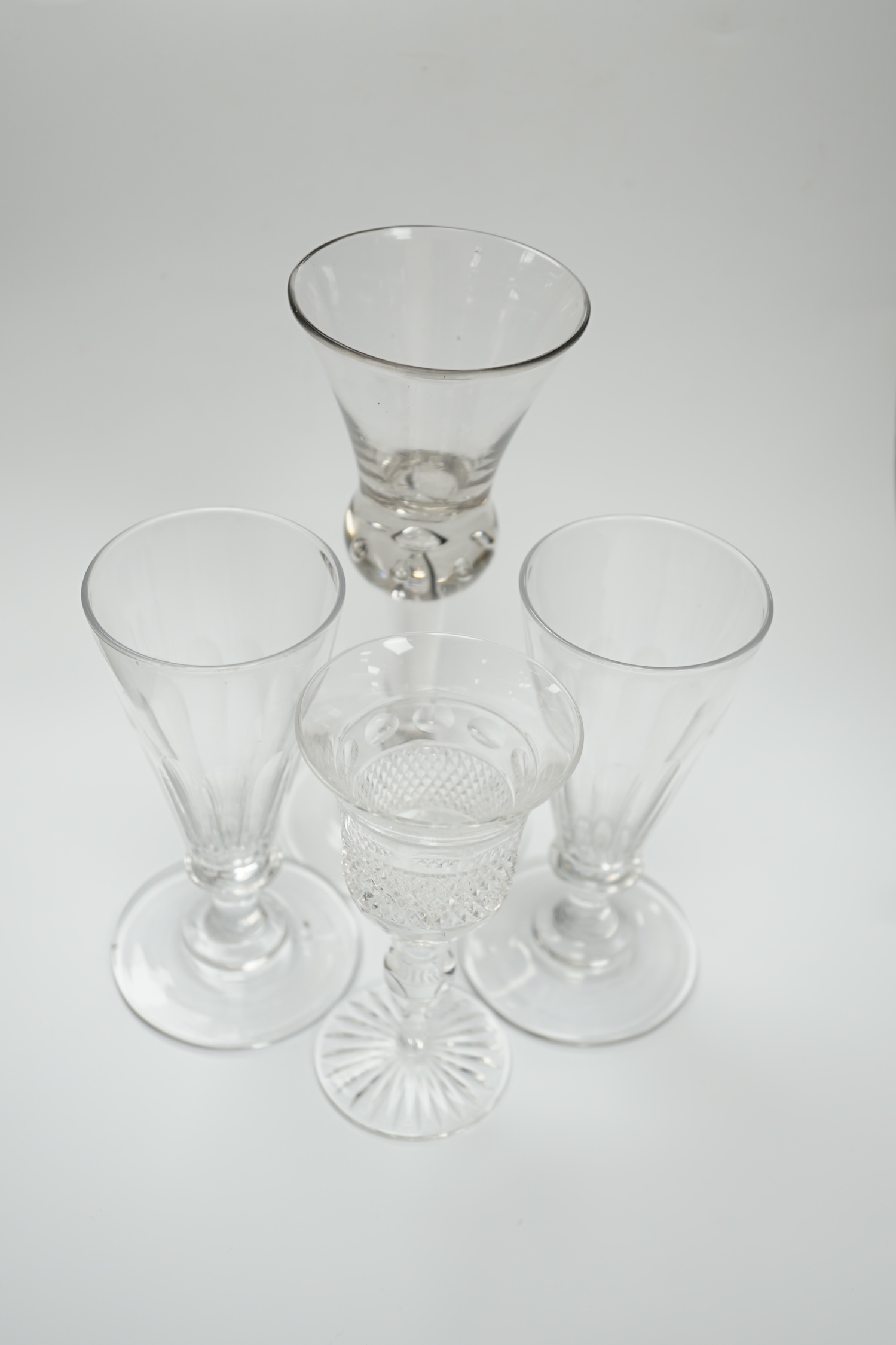 A pair of early 19th century dwarf ale glasses with fluted conical bowls, bladed knop stems and polished pontils, together with a mid-18th century thistle bowl glass with multiple air tears, plain stem and domed foot and